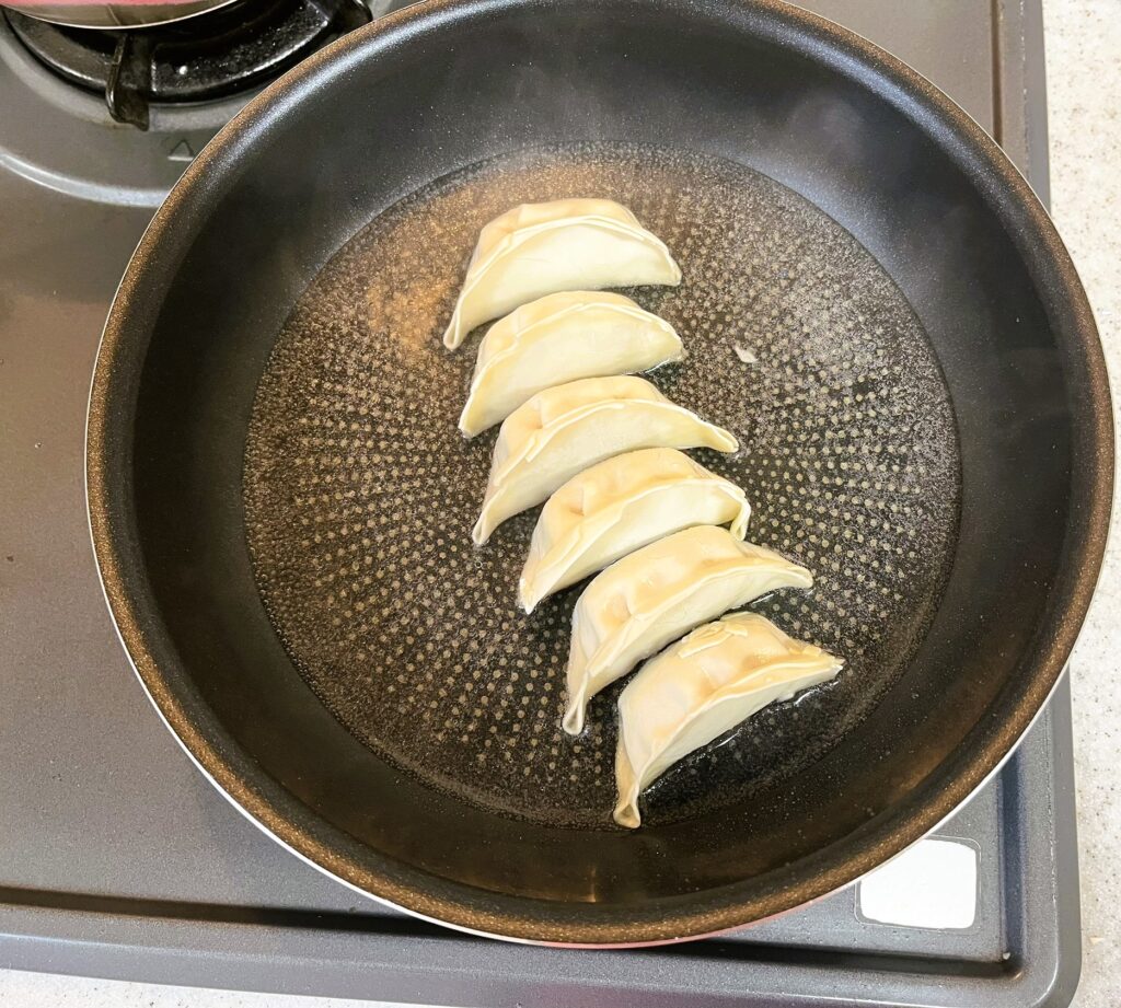 コストコ餃子計画の冷凍餃子の焼き方。餃子の3分の1まで水を入れて蒸し焼き。水を入れる時にはねるので、火を止めて少しずつ入れる。
